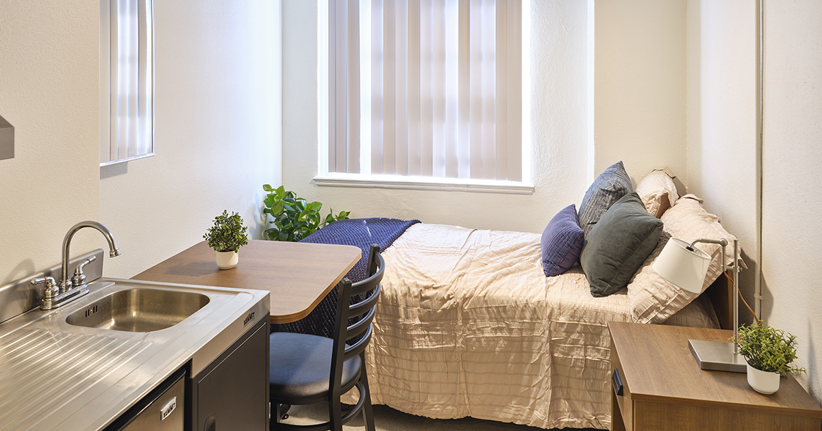 bedroom with small desk, end table and kitchenette
