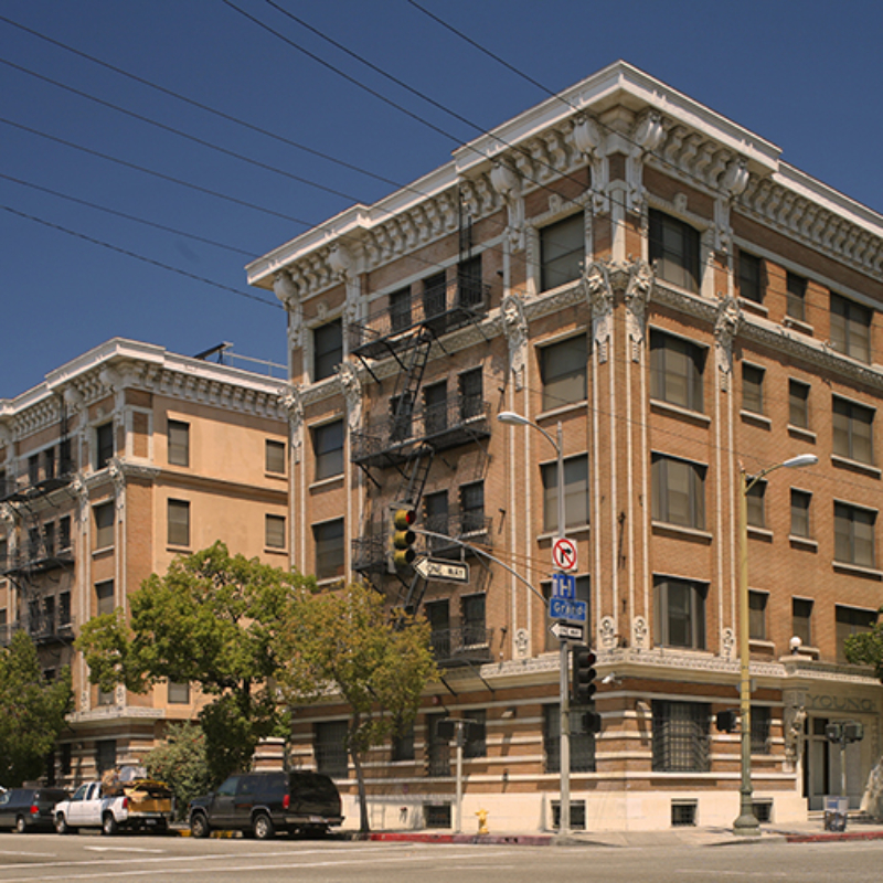 A historic, five-story building located on urban downtown corner featuring brick and large windows with cornices.